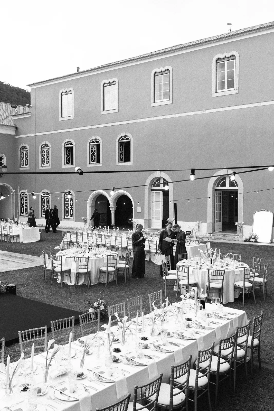 Wedding guests gathering under stone archway with floral arrangements