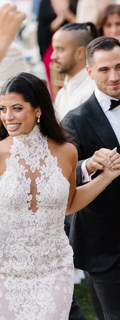 Aerial view of red vintage car driving through cypress avenue to white estate