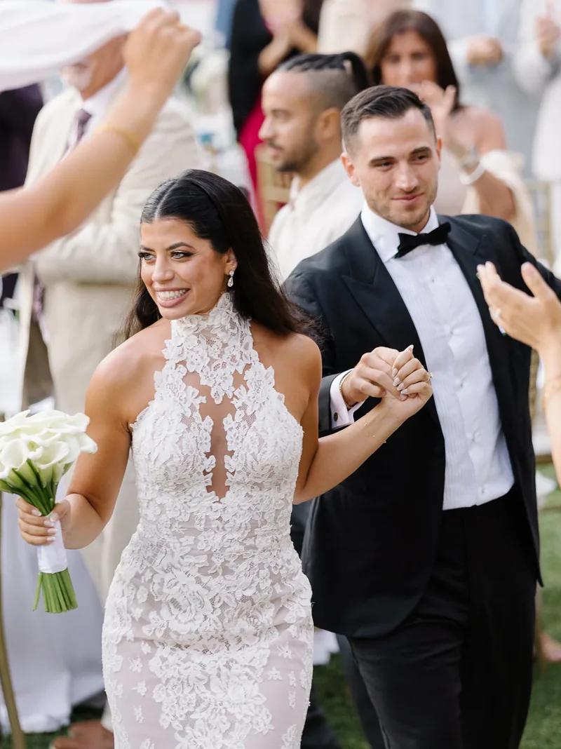 Aerial view of red vintage car driving through cypress avenue to white estate